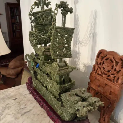 Sale Photo Thumbnail #44: Elaborately carved green jadeite or soapstone dragon boat sculpture with intricate sails and chains, resting on a fitted carved wooden base.
