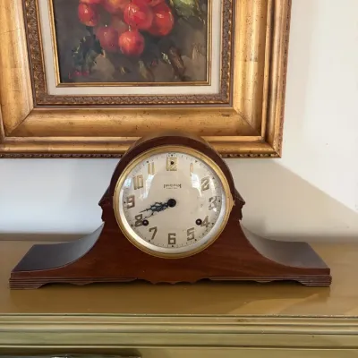 Sale Photo Thumbnail #107: Vintage Ingraham tambour mantle clock in a wooden case, positioned beneath a framed oil painting of fruit.