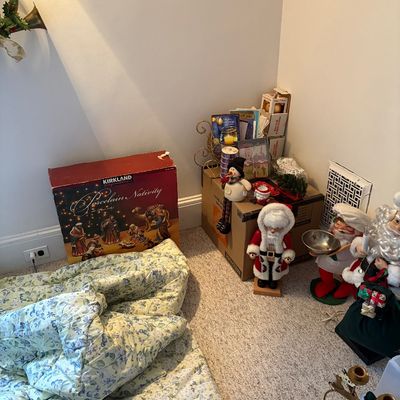 Sale Photo Thumbnail #15: Collection of Christmas decor including a boxed Kirkland Signature porcelain nativity set, standing Santa Claus and snowman figures, and a floral patterned comforter.