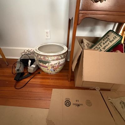Sale Photo Thumbnail #32: Large Chinese Famille Rose porcelain fishbowl planter sitting on hardwood flooring beside a cardboard box filled with pillows.
