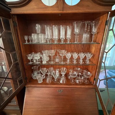 Sale Photo Thumbnail #30: Traditional mahogany secretary desk with a broken-pediment hutch top, filled with an extensive collection of cut and etched crystal glassware.