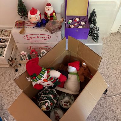 Sale Photo Thumbnail #14: Collection of assorted Christmas decor including plush snowmen, snow globes, vintage glass ornaments in a purple box, and Santa figurines.