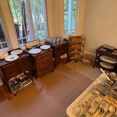 Sale Photo Thumbnail #46: Collection of traditional wooden nightstands and end tables displayed alongside tableware, stemware, flatware, and a tiered woven storage rack.