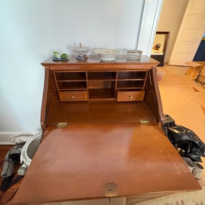 Sale Photo Thumbnail #31: Vintage slant-top writing desk with interior cubbies and drawers, topped with decorative glassware.