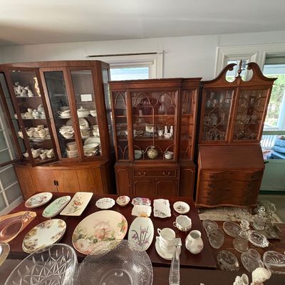 Sale Photo Thumbnail #35: Collection of vintage wooden display cabinets and hutch secretaries filled and surrounding tables with floral china plates, serving dishes, and cut crystal glassware.