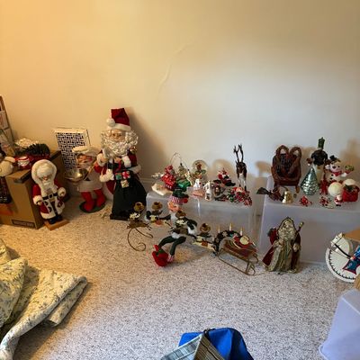 Sale Photo Thumbnail #12: Collection of vintage Christmas decorations and figurines, including standing Santa Claus statues, snowmen, and table decor displayed on storage bins.