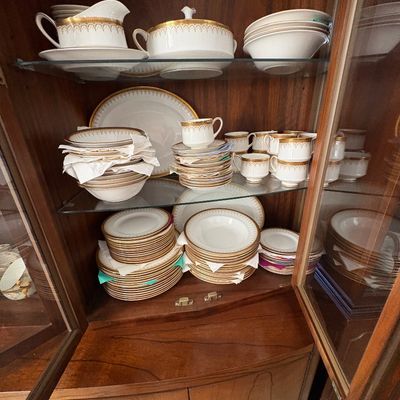 Sale Photo Thumbnail #26: Vintage white fine china dinnerware service with gold filigree rims, displayed inside a wooden corner china cabinet.