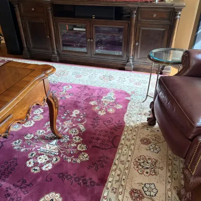 Traditional living room furniture including a large dark wood media console, a leather armchair with claw feet, a carved wooden coffee...