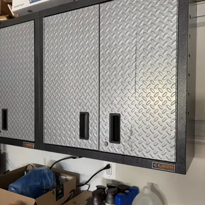 Gladiator wall-mounted metal garage storage cabinets with silver tread-plate door panels and black frames.