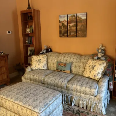 Traditional blue and white damask upholstered sofa with a matching skirted ottoman and accent pillows.