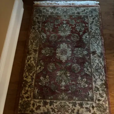 Traditional Persian-style area rug with a floral medallion pattern in muted burgundy and sage green tones, featuring fringe ends.