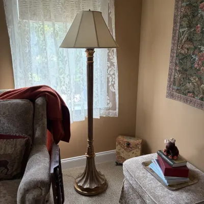 Traditional brass floor lamp featuring a fluted column, ornate classical accents, and a fabric lampshade, displayed alongside a matching...