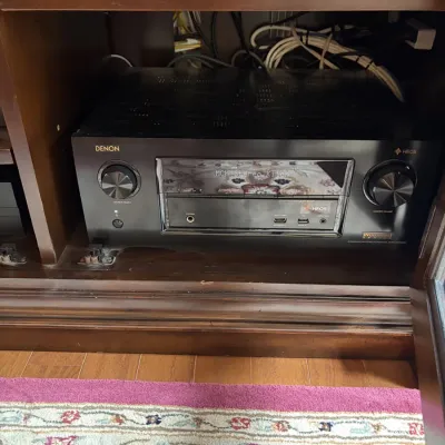 Denon IN-Command Series Integrated Network AV Receiver with HEOS built-in, housed inside a wooden media console.