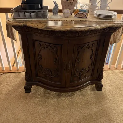Traditional carved wood accent console cabinet with a marble-style top, displayed as a coffee station with mugs and decor.