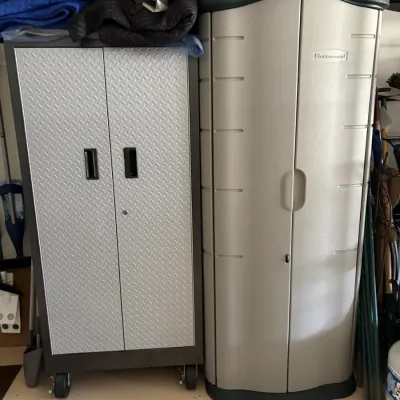 Metal rolling garage storage cabinet with diamond plate pattern doors standing beside a tall Rubbermaid resin storage cabinet.