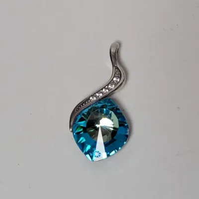 Contemporary sterling silver pendant featuring a faceted aquamarine-colored crystal topped with a paved wave bail.