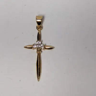 Gold cross pendant featuring tapered arms and a central cluster of small clear gemstones.
