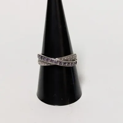 Sterling silver crisscross band ring featuring rows of pave-set clear and purple stones, displayed on a black ring cone.