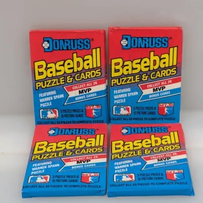 Four unopened wax packs of 1988 Donruss Baseball Puzzle & Cards, featuring Warren Spahn puzzle pieces.