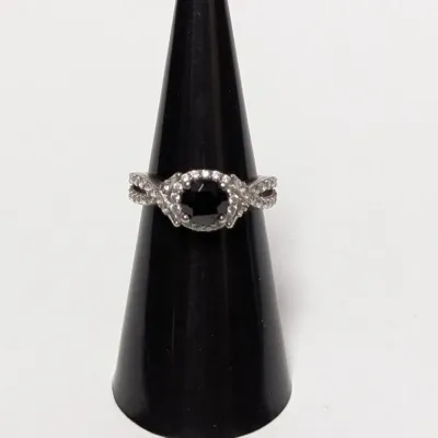 Silver-tone halo ring featuring a round black center stone surrounded by pavé accent stones on a split-infinity band, displayed on a...