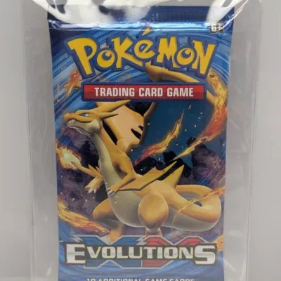 Sealed Pokémon XY Evolutions booster pack featuring Mega Charizard Y artwork, housed in a protective plastic sleeve.