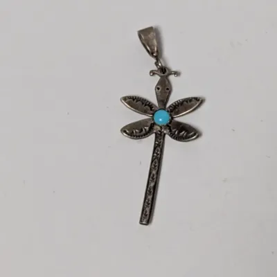 Native American style sterling silver dragonfly pendant featuring a round turquoise cabochon center and stamped detailing.