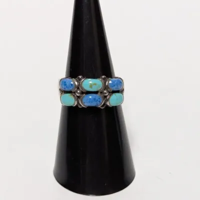 Native American style sterling silver ring set with alternating turquoise and lapis lazuli cabochons, displayed on a black ring cone.