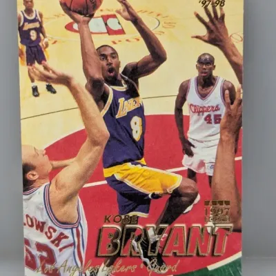 1997-98 Fleer Kobe Bryant basketball trading card depicting him driving to the basket in his Los Angeles Lakers uniform.