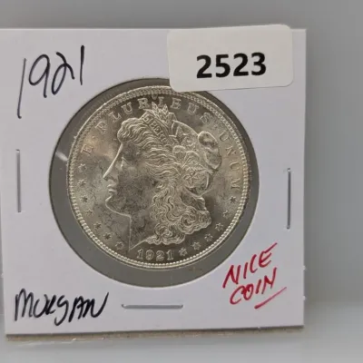 1921 Morgan silver dollar, presented in a cardboard flip holder.