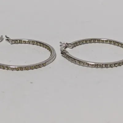 Pair of silver-tone inside-out hoop earrings set with small light yellow crystal accents.