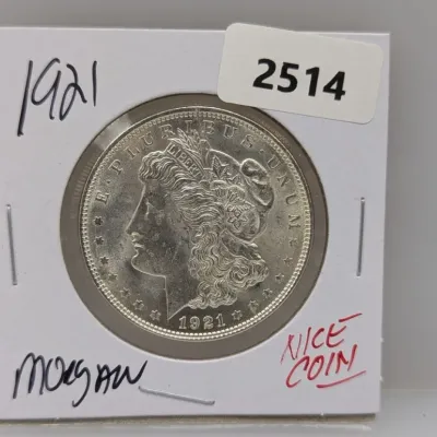 1921 Morgan silver dollar housed in a cardboard coin flip holder.
