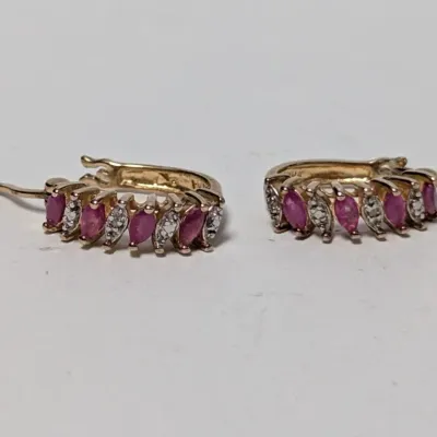Pair of gold huggie hoop earrings set with marquise-cut pink rubies and small diamond accents.