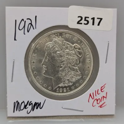 1921 Morgan silver dollar housed in a cardboard flip holder with handwritten notes.