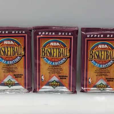 Three unopened packs of 1991-92 Upper Deck NBA Basketball Inaugural Edition trading cards.