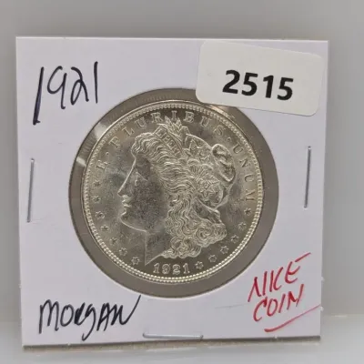 1921 Morgan silver dollar, housed in a cardboard flip holder.