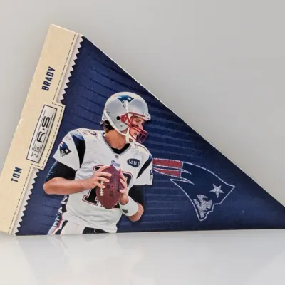 Panini Rookies & Stars Tom Brady triangular pennant-style trading card featuring him in a New England Patriots uniform.