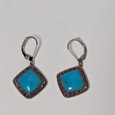 Pair of sterling silver leverback dangle earrings featuring square-cut turquoise stones framed by marcasite borders.