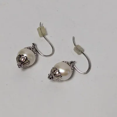 Pair of faux pearl dangle earrings with silver-tone filigree caps and French hook ear wires.