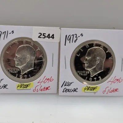Pair of Eisenhower proof silver dollars, including a 1971-S and a 1973-S, housed in protective cardboard coin flips.