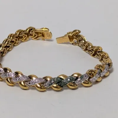 Two-tone gold and diamond-accented link bracelet with a fold-over clasp and safety latch.