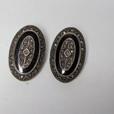 Vintage Art Deco style oval clip-on earrings featuring black onyx panels and marcasite embellishments in silver-tone metal settings.