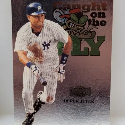 1998 Metal Universe 'Caught on the Fly' Derek Jeter baseball trading card #12. Features metallic foil finish depicting the New...