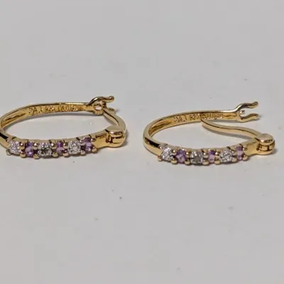 Pair of PAJ 925 gold-plated sterling silver hoop earrings, featuring channel-set purple and clear accent stones.