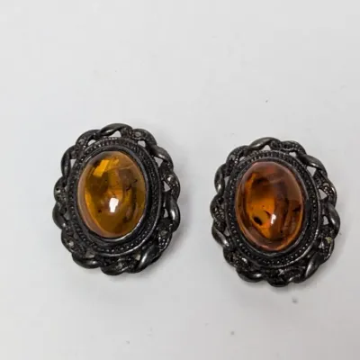 Vintage sterling silver and amber cabochon clip-on earrings featuring ornate filigree and marcasite details.