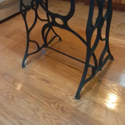 Small accent table repurposing a vintage black cast iron sewing machine base topped with a light wood surface.