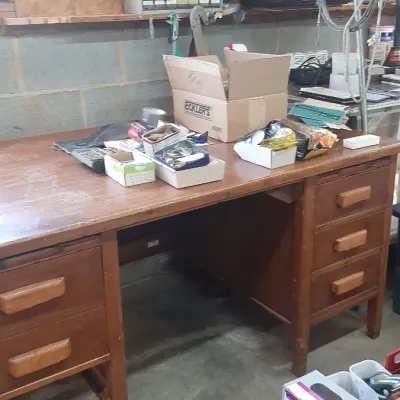 Large vintage wooden workshop desk with multiple drawers, topped with various small hardware and organization boxes.