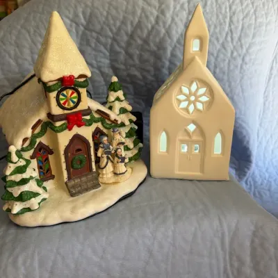 Two-piece holiday décor lot includes a snow-covered ceramic Christmas house with family figures and 