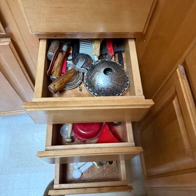 Sale Photo Thumbnail #41: Open wooden kitchen drawers containing various vintage utensils and gadgets, including a metal steamer basket, pastry cutters, and measuring spoons.