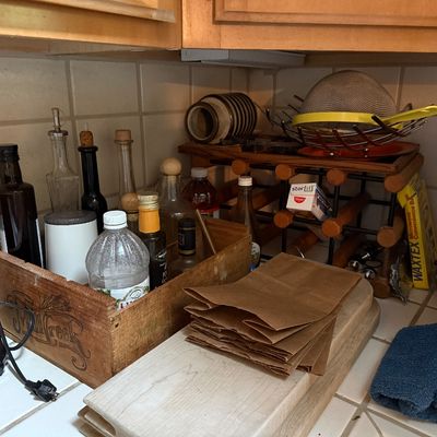 Sale Photo Thumbnail #29: Kitchen countertop display featuring a wooden Mill Creek crate with oil and vinegar bottles, a stackable wooden wine rack, a Nostalgia hot air popcorn popper, and wooden cutting boards.