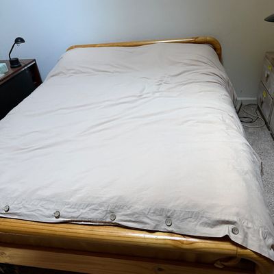 Sale Photo Thumbnail #63: Natural pine wood platform bed frame dressed with a buttoned beige comforter or duvet.